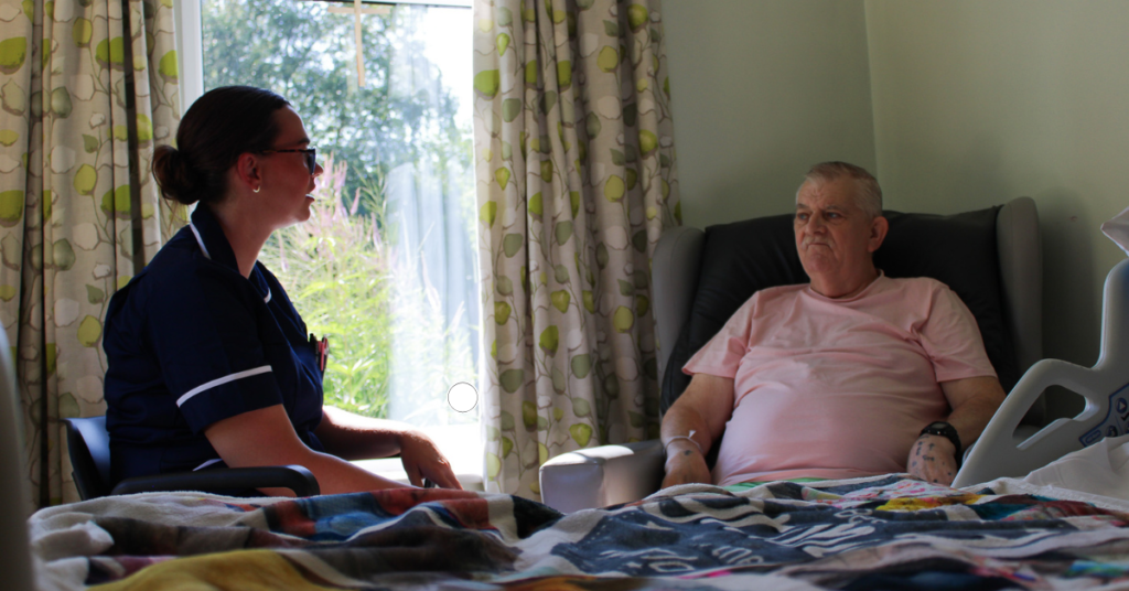 Heather Dainty, Deputy Ward Manager at Wigan & Leigh Hospice, chatting to a patient on the Inpatient Unit.